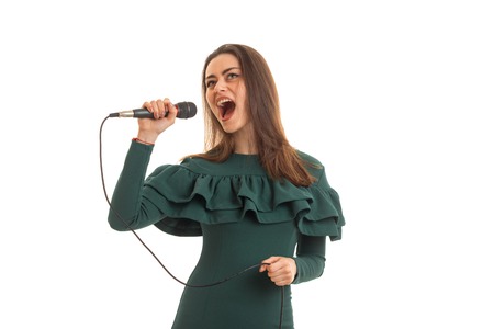 Beautiful woman sings in microphone a karaoke in green dress isolated on white backgroundの写真素材