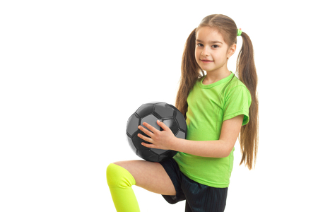 little girl with tails in green t-shirt holding a ball, isolated on white backgroundの写真素材
