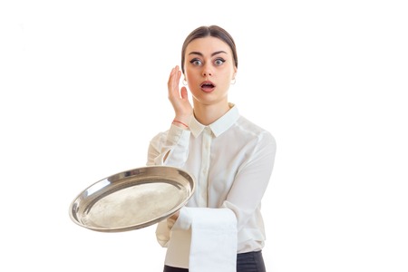 surprised young waitress with trey in hands in uniform isolated on white backgroundの写真素材