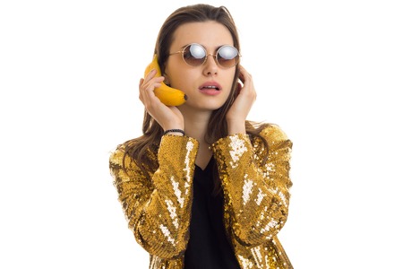 young stylish woman in golden jacket with banana isolated on white backgroundの写真素材