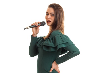 Beautiful lady in green dress with microphone isolated on white backgroundの写真素材