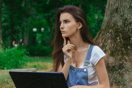 beautiful thoughtful Lady with the laptop in the Park close-upの写真素材