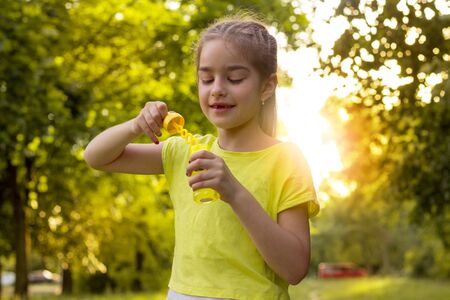 joyful little girl standing on the street with soap bubbles in the hands of close-upの写真素材
