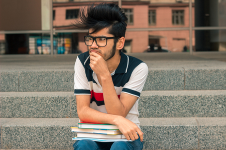 horizontal portrait of charming young man in glasses and booksの写真素材