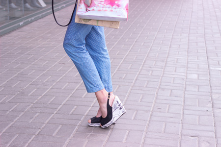 elegant woman on high heels with shopping bags in hands outdoorsの写真素材