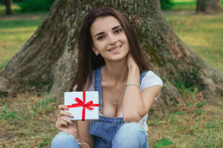 cheerful young girl at the park with present in her hands smiling on camera outdoorsの写真素材