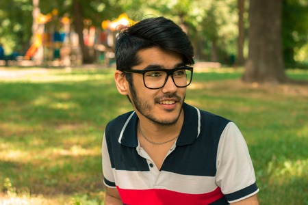 a close-up portrait of young smiling guy in glasses in the Parkの写真素材