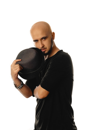 glamour unshaved man wearing black with hat in his hands posing isolated on white backgroundの写真素材