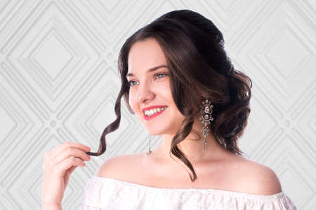 Young sweet brunette with beautiful hairstyle posing in studio