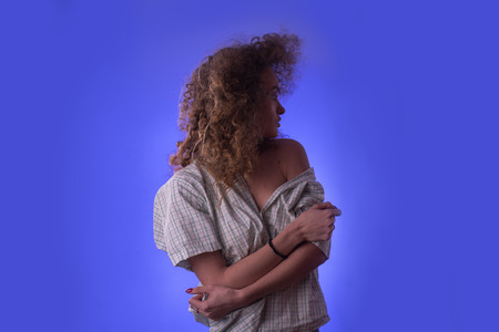 Beautiful young girl with afro hairstyle and colourful make up in studio on blue backgroundの写真素材