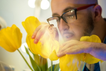 handsome scientist in glasses grew a sexy girl in the yellow blooming flowerの写真素材