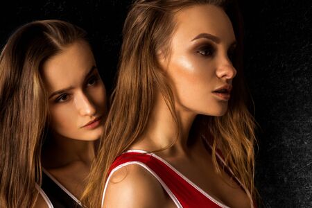 Young slim sexy girls in body suits in studio on black background