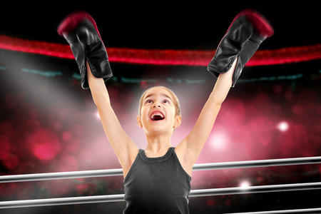happy little girl boxer win a fight in a ringの写真素材