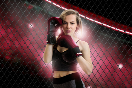 charming blonde woman mma fighter in red corner of the cage looking at the cameraの写真素材
