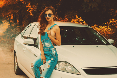 young gorgeous women in sunglasses sexy sits on a white car in autumn timeの写真素材