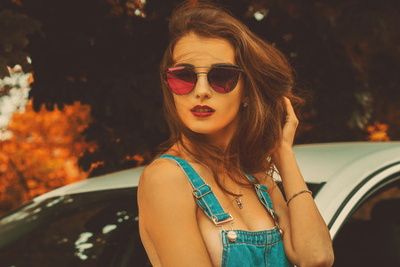 portrait of young beautiful brunette in sunglasses outdoors in the autumnの写真素材