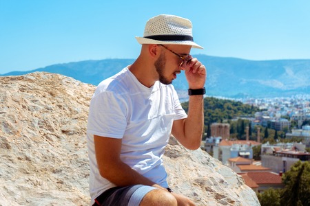 stylish young man un sunglasses looks at the city view from the high hillの写真素材