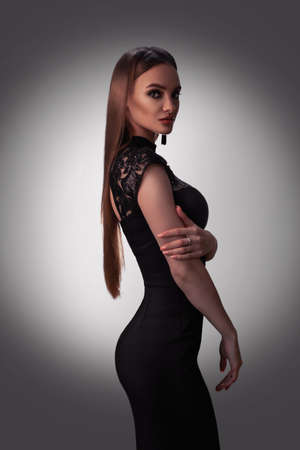 Sexy young lady with beautiful makeup in black dress posing in studio. Fashion model in black dressの写真素材