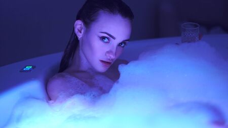 Beautiful girl in the bathroom with foam looking at the cameraの写真素材