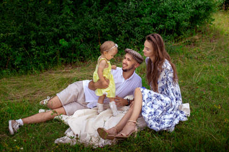 portrait of young happy family plays with their liitle baby daughter at the green meadowの写真素材