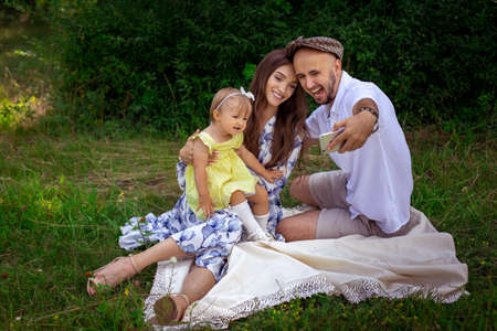 portrait of young happy family plays with their liitle baby daughter at the green meadowの写真素材