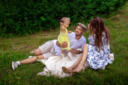 portrait of young happy family plays with their liitle baby daughter at the green meadowの写真素材