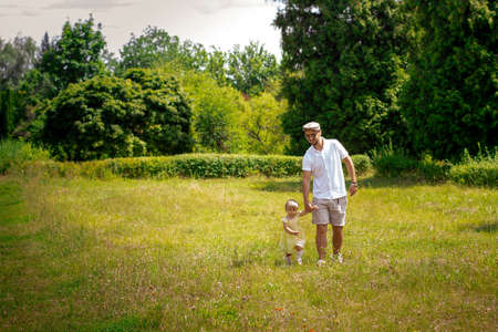 dad walks with his little baby daughter at the meadow summer timeの写真素材