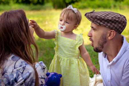 Cutie little baby girl touches her mothers nose at the family picnic at the parkの写真素材