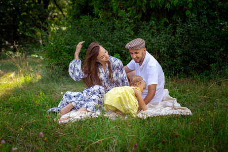 portrait of happy young family plays with their liitle baby daughter at the green meadowの写真素材