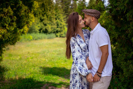 horizontal portrait of couple in love hugs and smiles holding hands at the green gardenの写真素材