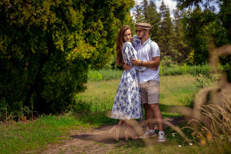 Beautiful couple in love holds hands and looking at each others at the green gardenの写真素材