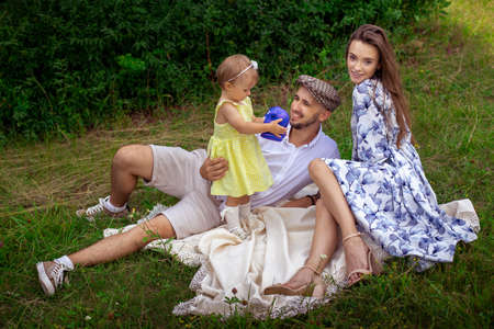 young caucasian family with daughter relaxing outdoors. Happy parents having fun at the park.の写真素材