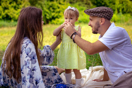 portrait of Happy family having fun at the park. Parents with daughter relaxing outdoors.の写真素材