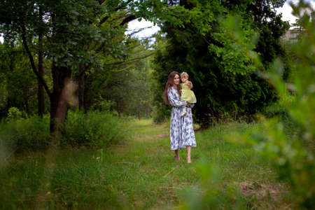 pretty young woman walks carrying little daughter at the gardenの写真素材