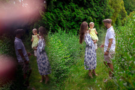 Young family carrying their little daughter ad the green park at warm summer dayの写真素材