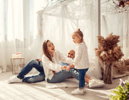 Young family at home in ltgh bedroom with thier daughter. Family time at homeの写真素材