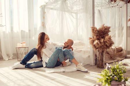 Beautiful couple in love hugs and kisses in white room at homeの写真素材