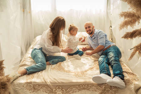 Happy family playing in bedroom. Family time with little daughter at homeの写真素材