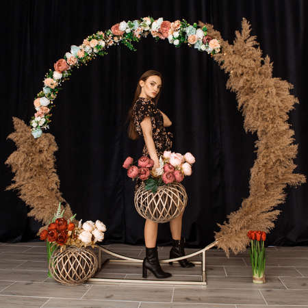 Beautiful woman posing at circle of deadwood in dress with flower print in studioの写真素材