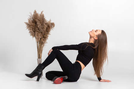 beautiful young woman in black clothes posing in studio on gray backgroundの写真素材