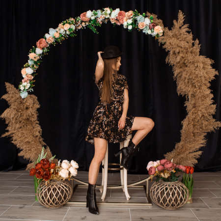Beautiful woman posing at circle of deadwood in dress with flower print in studioの写真素材