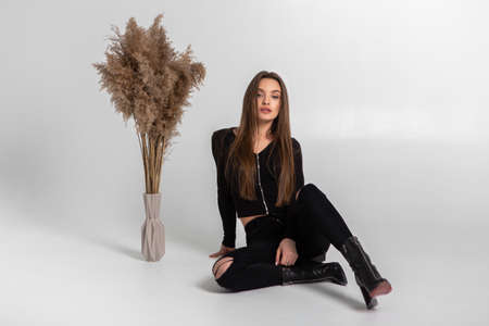 beautiful young woman in black clothes posing in studio on gray backgroundの写真素材