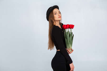 portrait of a beautiful girl in a hat with tulips in hands in studioの写真素材