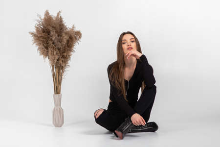 beautiful young woman in black clothes posing in studio on gray backgroundの写真素材