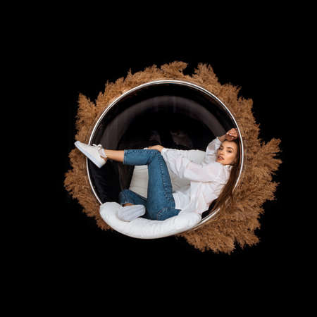 glamor woman sits in circle chair with deadwood around in studioの写真素材