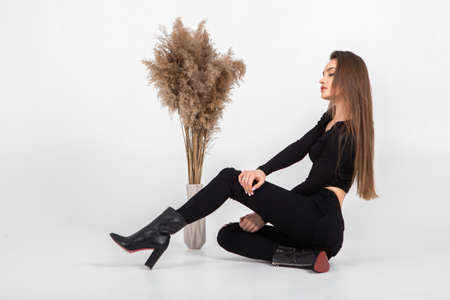 beautiful young woman in black clothes posing in studio on gray backgroundの写真素材