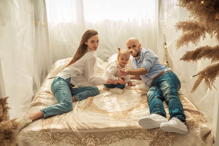 Happy family playing in bedroom. Family time with little daughter at homeの写真素材
