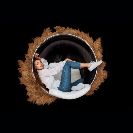 glamor woman sits in circle chair with deadwood around in studioの写真素材