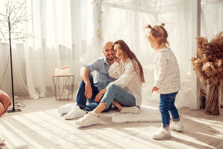 Young family at home in ltgh bedroom with thier daughter. Family time at homeの写真素材