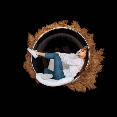 glamor woman sits in circle chair with deadwood around in studioの写真素材